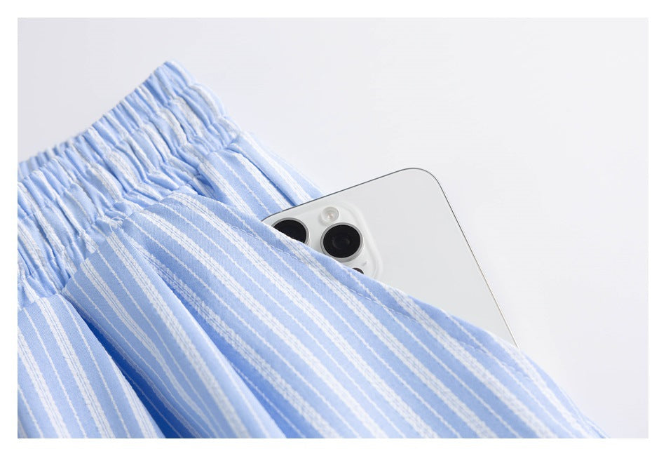 Close-up of a pocket on light blue and white striped shorts holding a white smartphone.