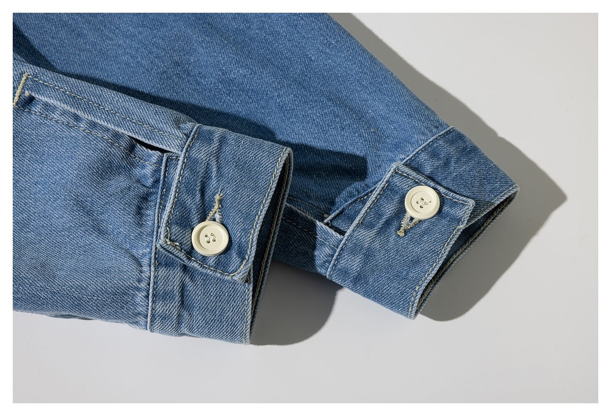 Close-up of a blue denim sleeve cuff with two cream buttons and contrast stitching.