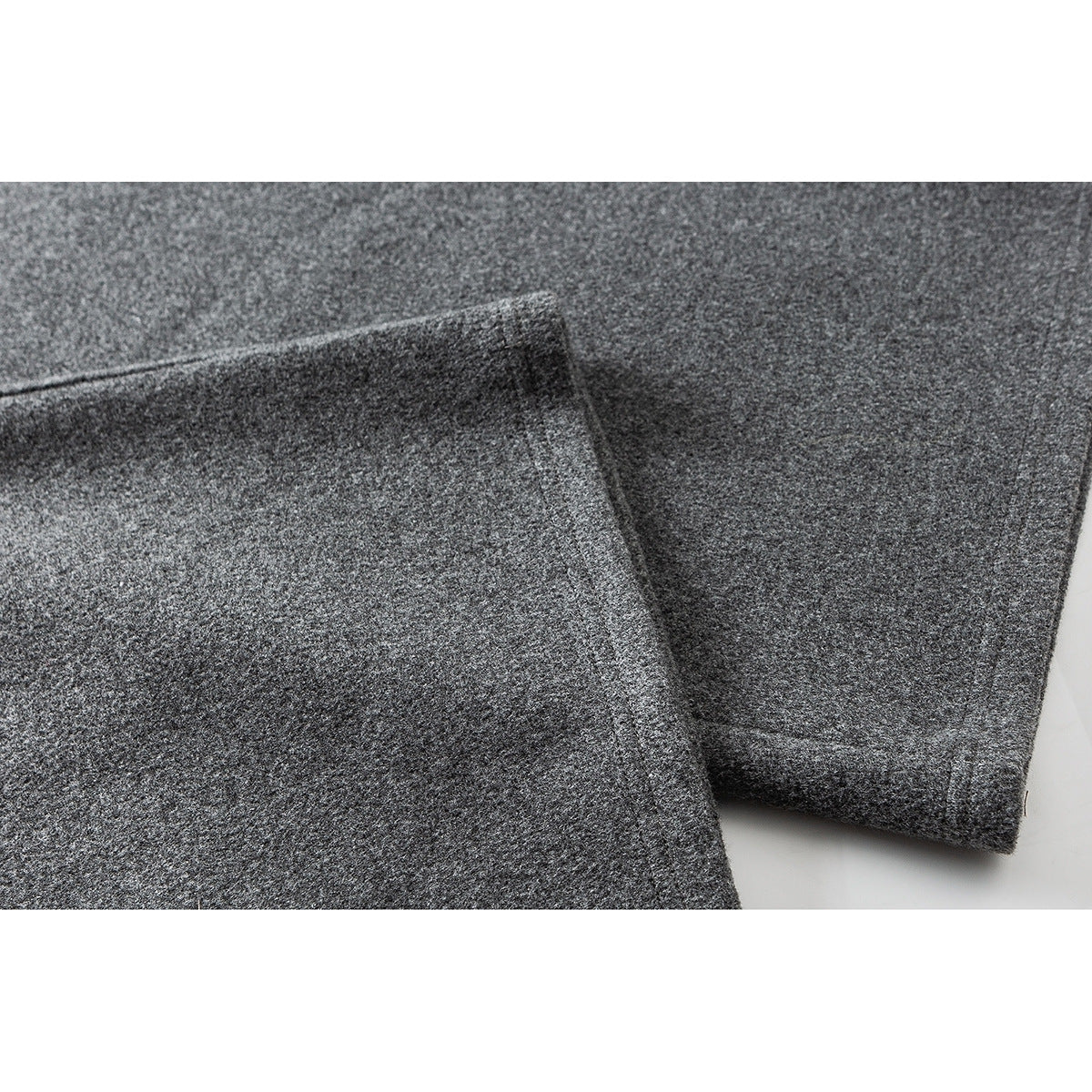Close-up of a gray pant leg and stitched hem, showing the fabric texture.