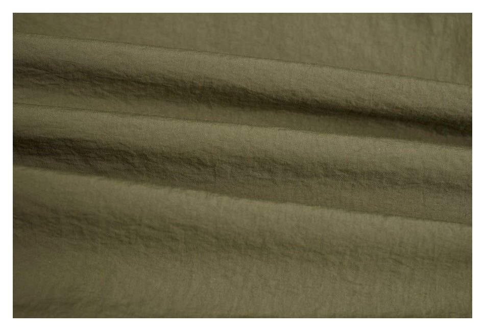 Close-up of olive green fabric with soft folds and a subtle textured surface.