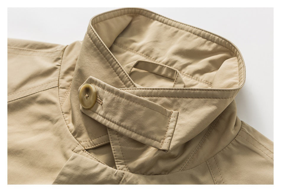 Close-up of a tan coat’s high collar and buttoned throat latch with visible stitching.