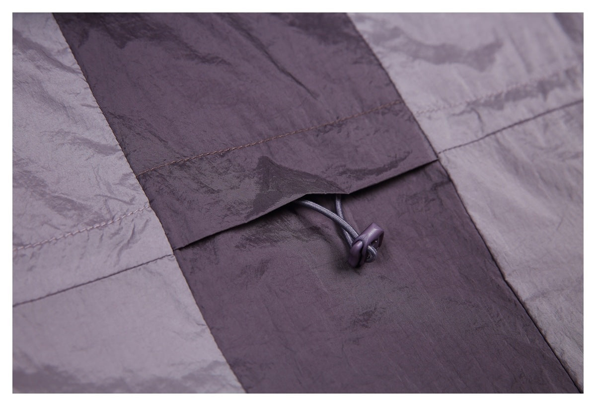 Close-up of a dark mauve garment panel with stitched seams and an adjustable drawcord toggle.