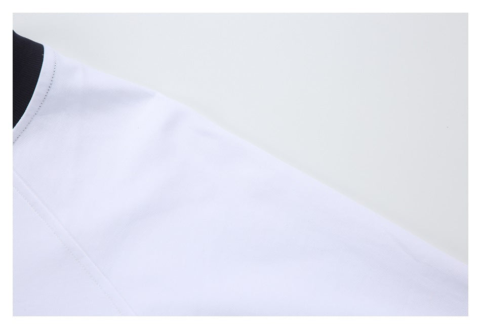 Close-up of the white shirt's sleeve and shoulder seam, with part of the black neckline visible.