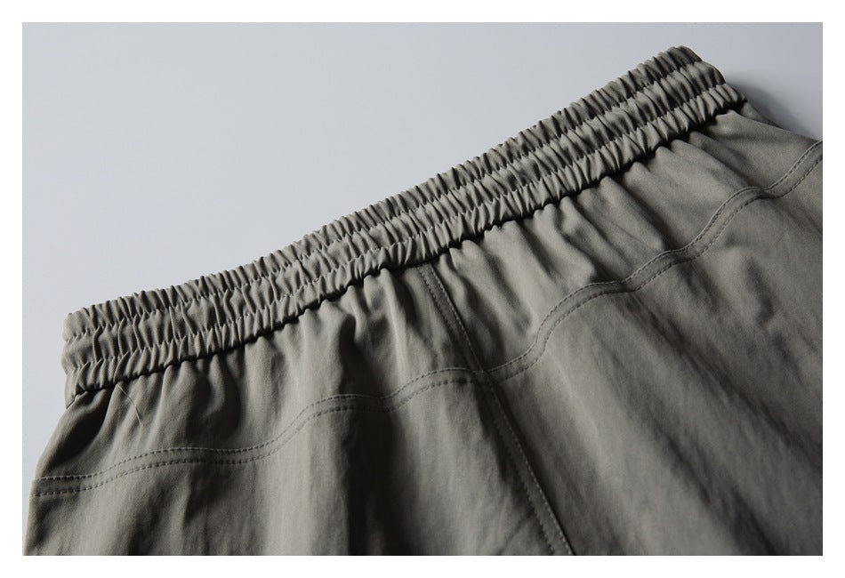 Close-up of gray shorts showing the gathered elastic waistband and stitched rear pocket seams.