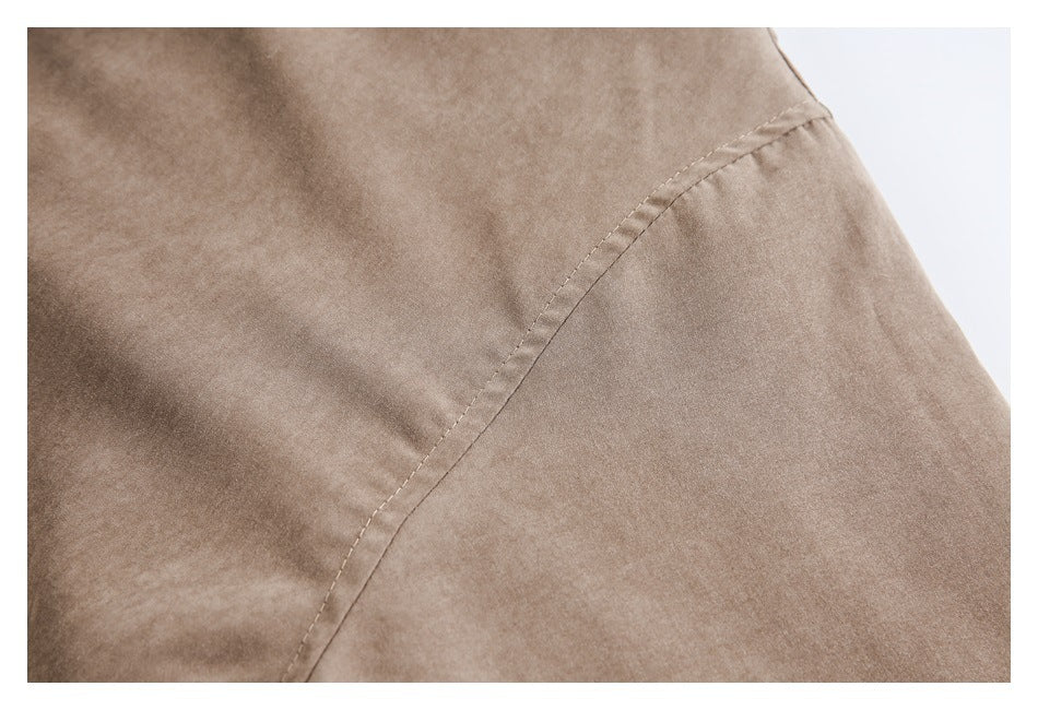 Close-up of a curved stitched seam on taupe coat fabric.
