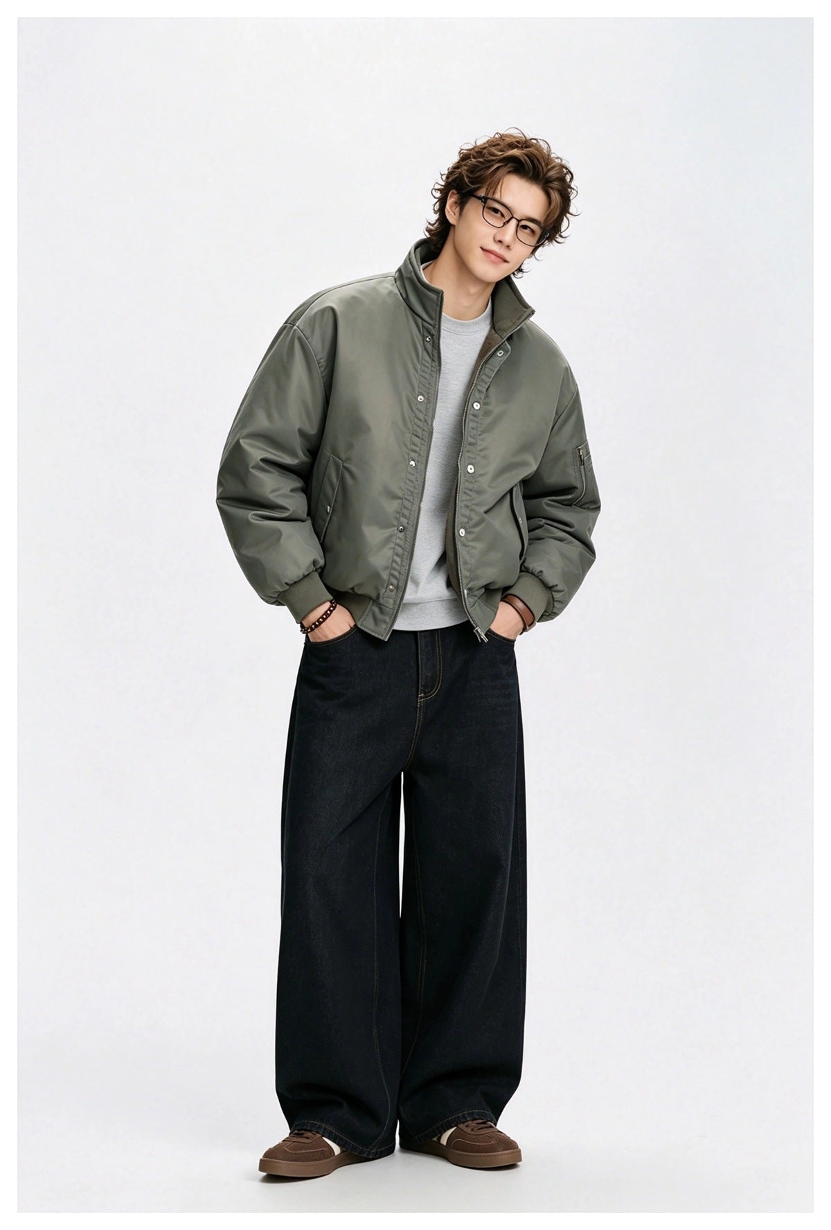 Man wearing an open olive green bomber-style jacket over a gray sweatshirt with wide-leg dark jeans and brown sneakers