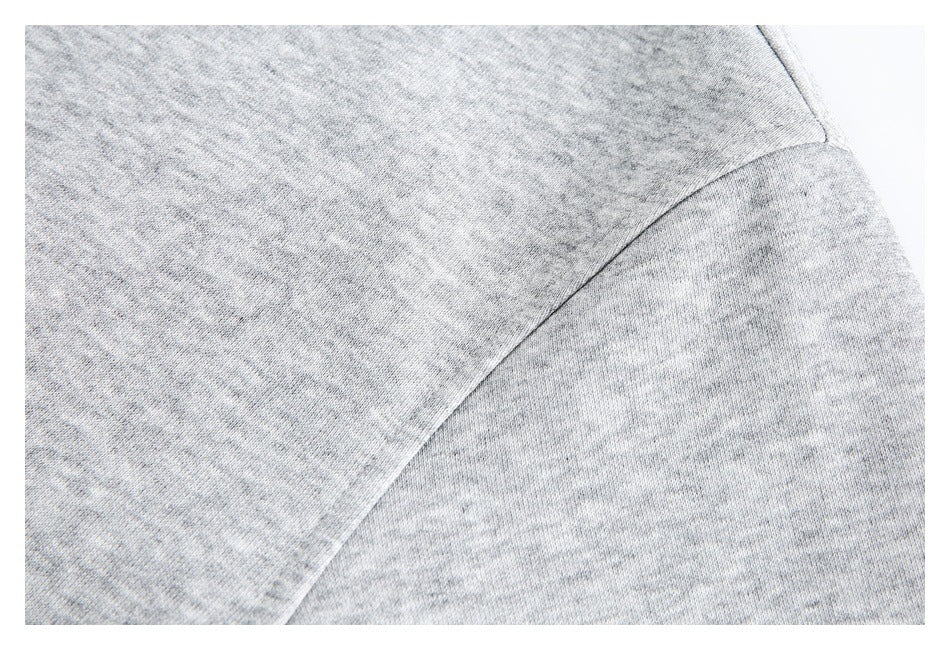 Close-up of light gray heathered fabric with a curved stitched seam.