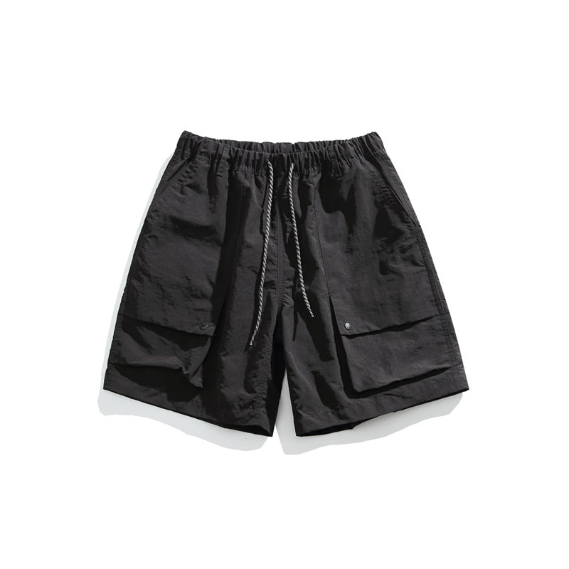 Black men's drawstring shorts with large front flap pockets and snap closures, flat lay front view