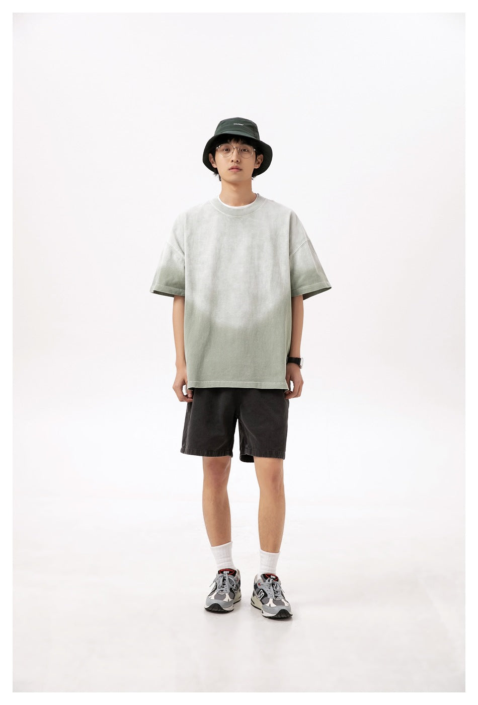 Full-length model wearing a pale sage-gray oversized short-sleeve T-shirt, shown from the front.