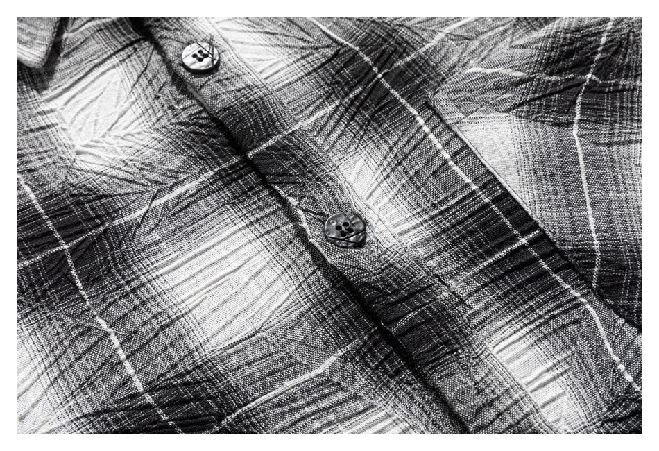 Close-up of the black, gray, and white plaid shirt front placket with two buttons.