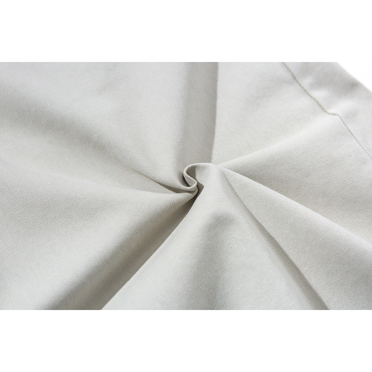 Close-up of light gray fabric gathered into folds, showing its fine diagonal weave.