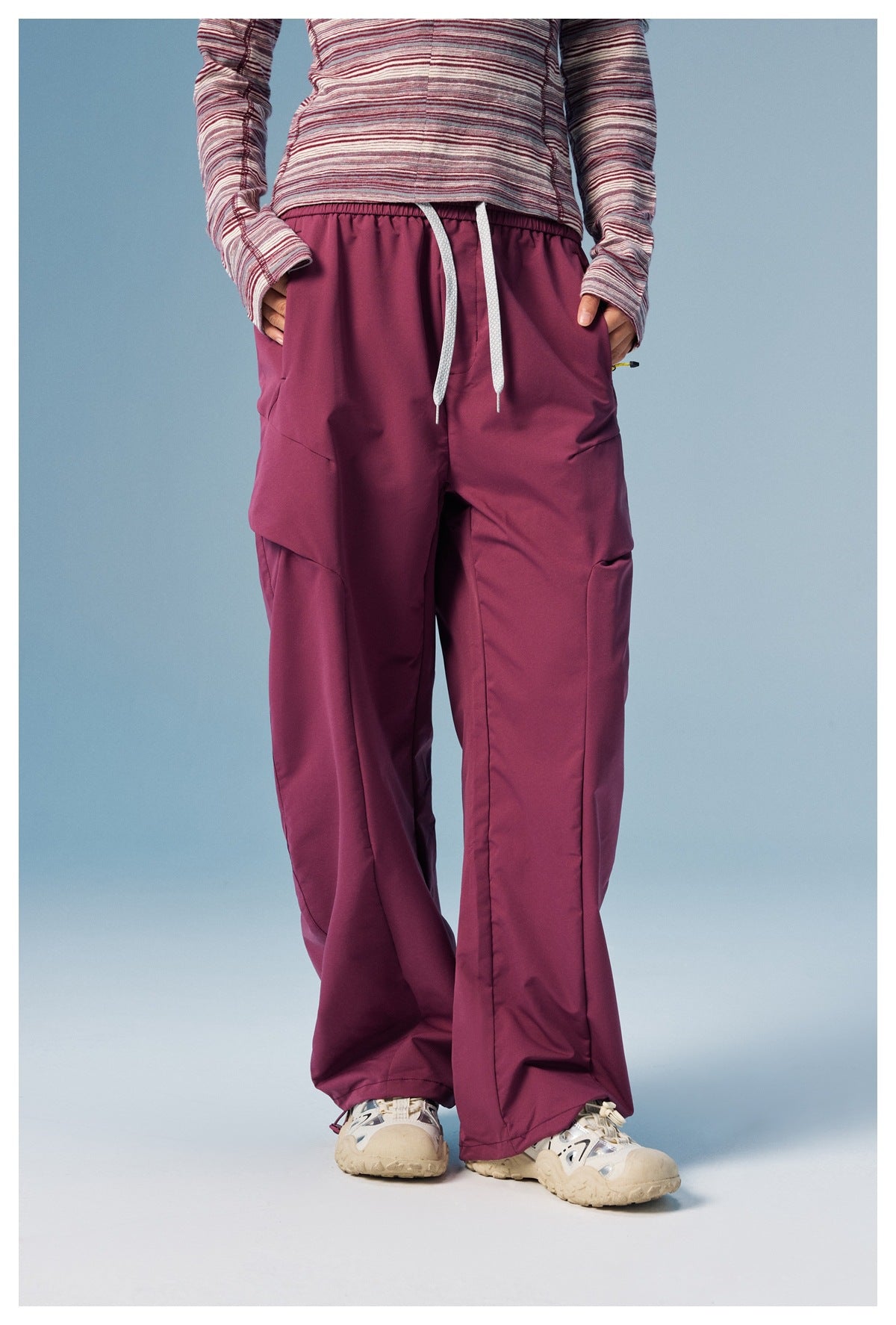 Front view of a person wearing loose plum cargo pants with a drawstring waist and layered side pockets.