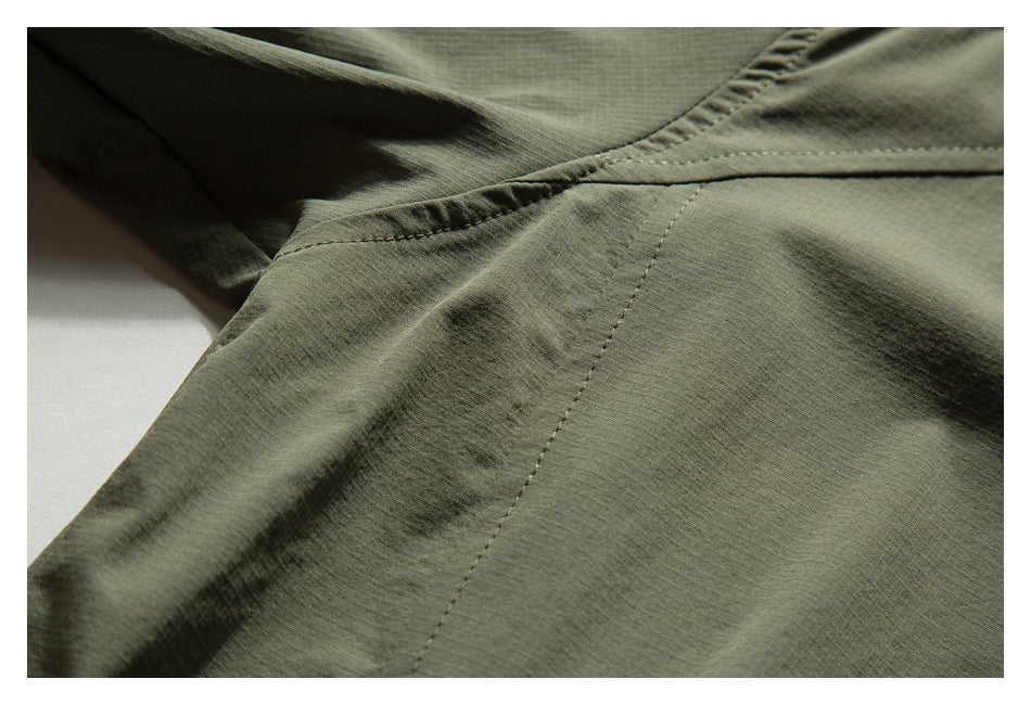 Close-up of olive-green garment fabric showing intersecting stitched seams.