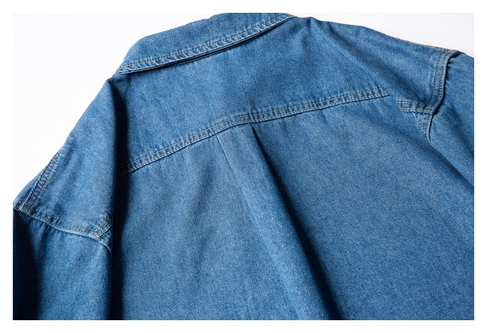 Flat lay of a blue denim shirt's upper back, showing the collar, shoulder seams, and yoke.