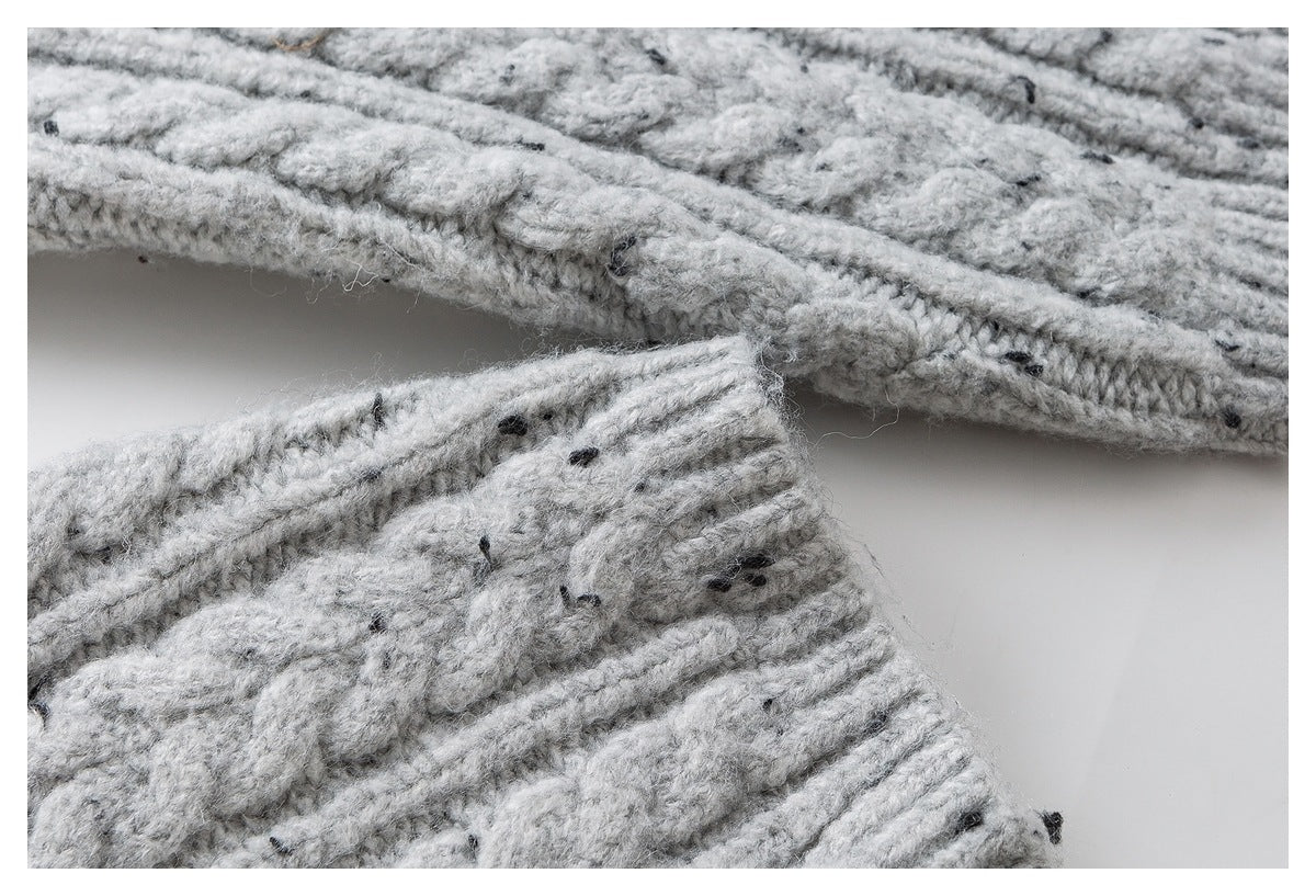 Close-up of the edge and seam of a light gray flecked cable-knit sweater.