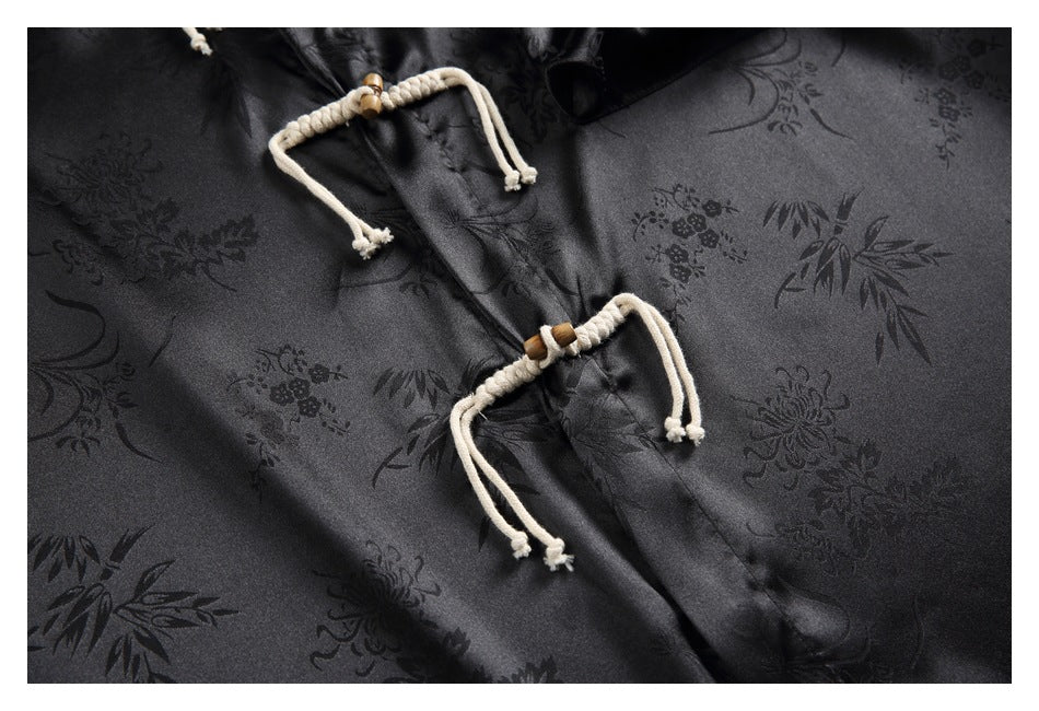 Close-up of a black floral-patterned shirt with two cream rope frog closures and wooden toggles.
