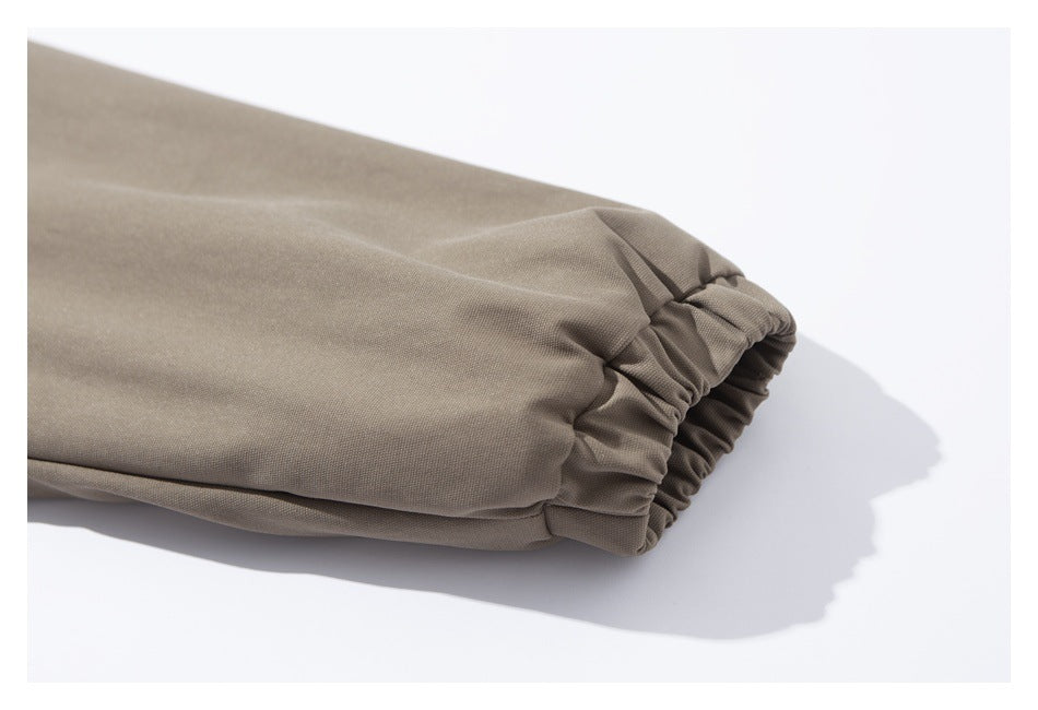 Close-up of a taupe jacket sleeve ending in a gathered elastic cuff.