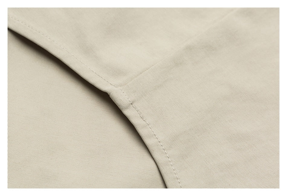 Close-up of beige garment fabric with a curved stitched seam and overlapping panel.