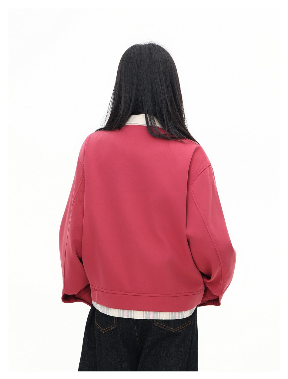 Back view of a model wearing a rose-pink jacket with a cream collar and plaid fabric showing below the hem.