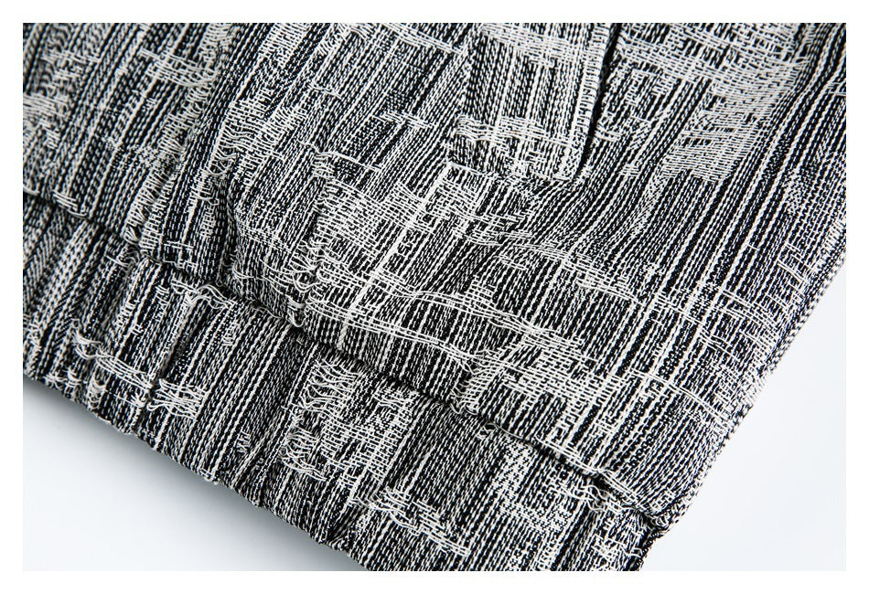 Close-up of a stitched edge on black-and-white patterned fabric, with loose threads visible.