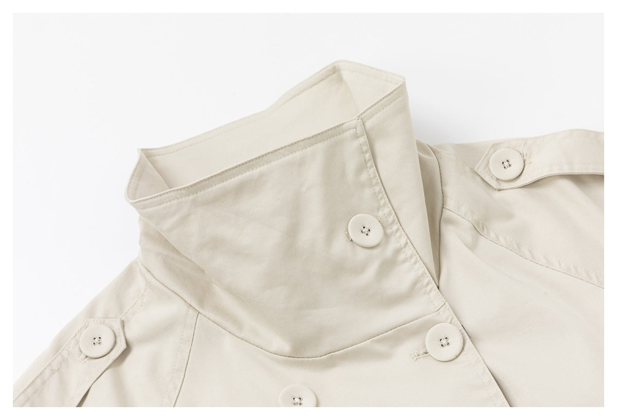 Close-up of the light beige coat's raised collar, shoulder tab, and matching front buttons.