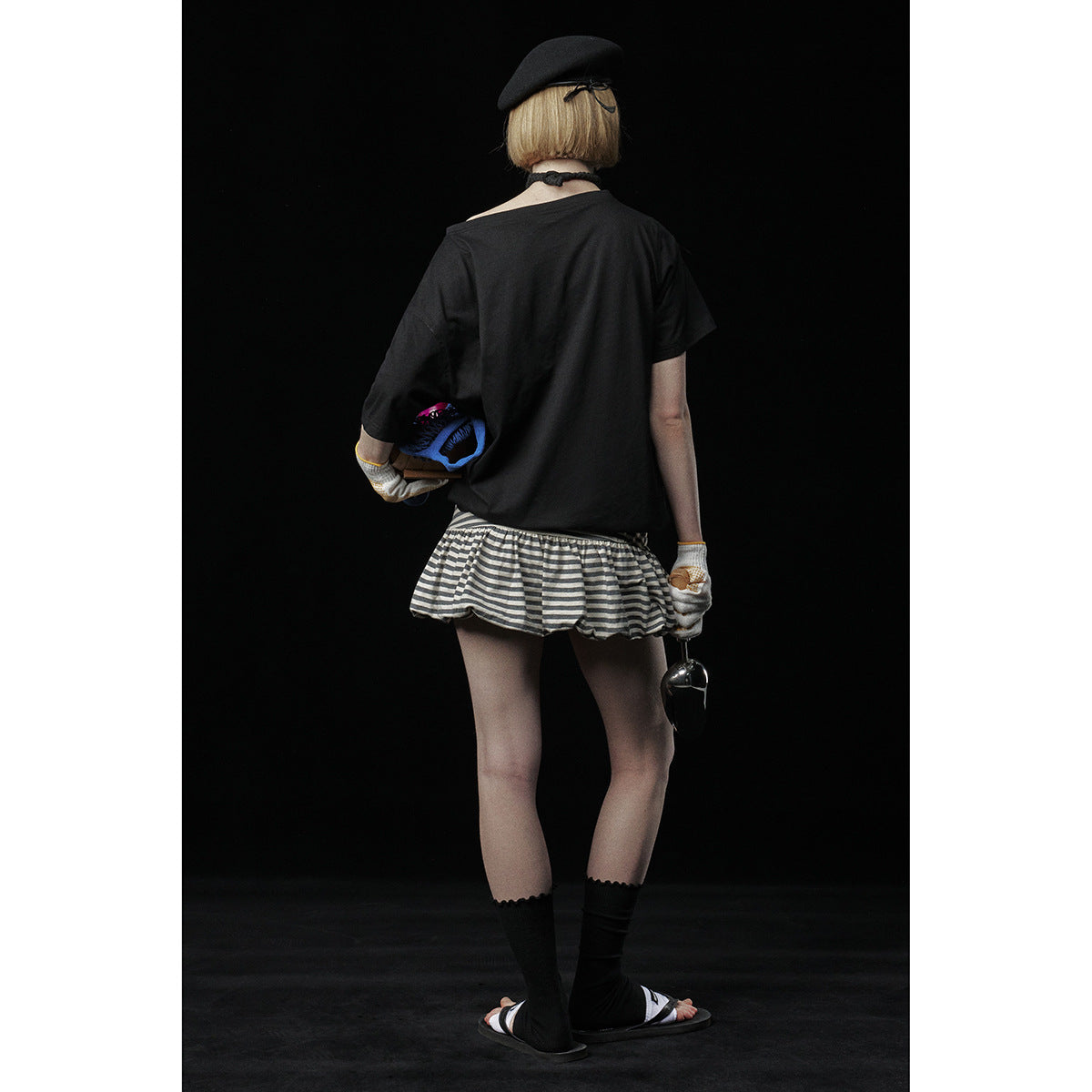 Rear view of a model wearing a loose black T-shirt and gray-and-black striped ruffle skirt.