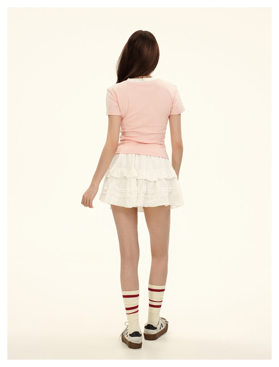Back view of a model wearing the pale pink short-sleeve top and a white tiered skirt.