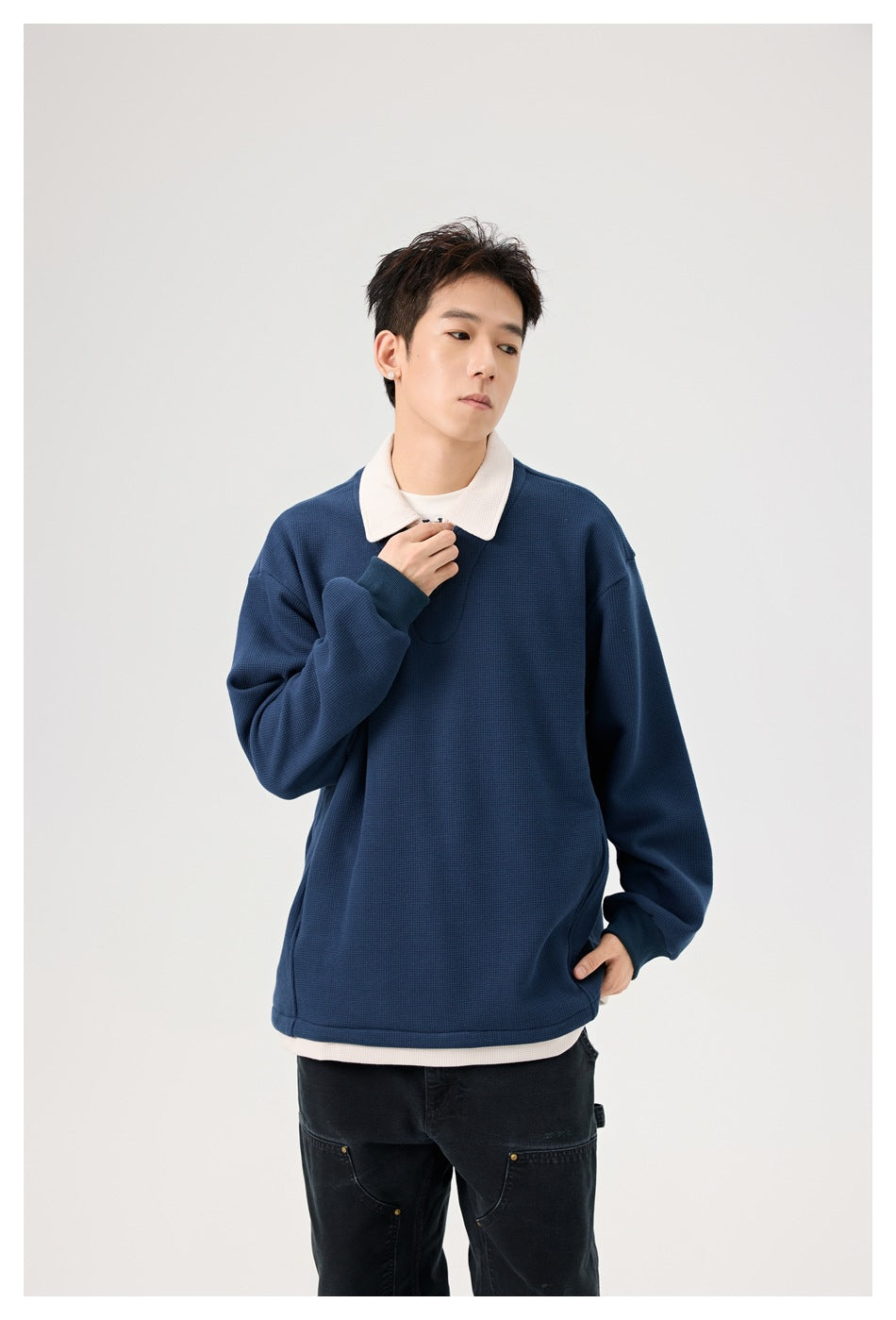 Model wearing a navy pullover with a white collar and short zip placket, shown in a closer view.