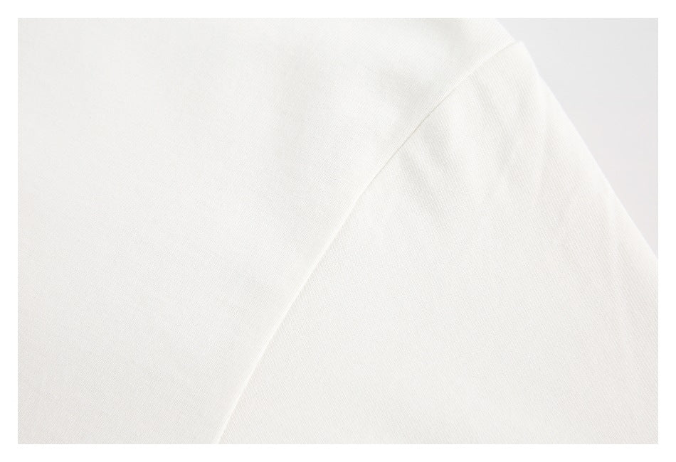 Close-up of plain off-white shirt fabric showing a shoulder seam.