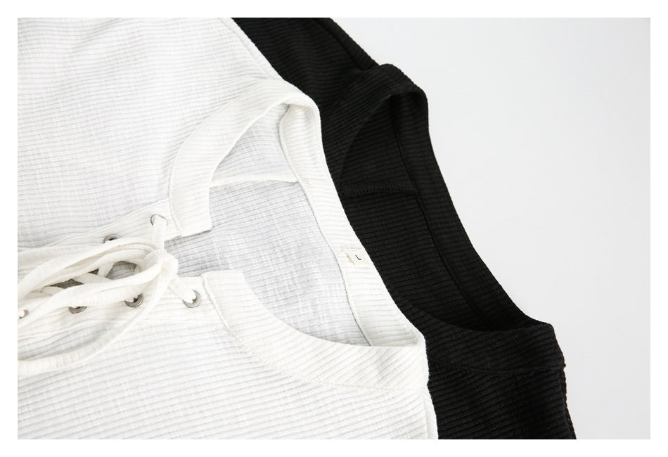 Close-up of white and black ribbed tops showing the neckline, fabric texture, and part of the lace-up front.