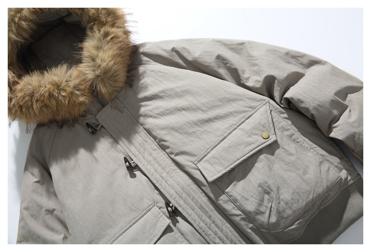 Close-up of the light gray jacket's toggle closures, flap pocket, fur-trimmed hood, and ribbed hem.