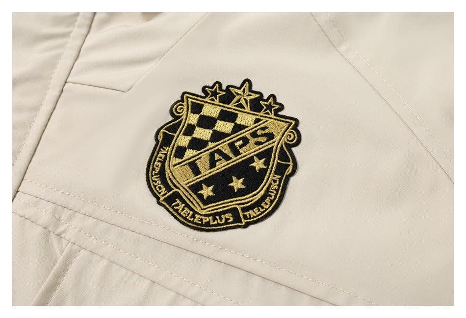 Close-up of a cream garment with a black-and-gold embroidered crest.