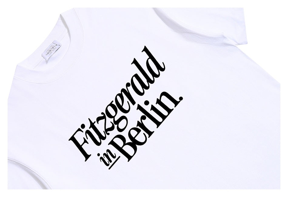 Close-up of a white T-shirt with large black “Fitzgerald in Berlin” chest lettering.