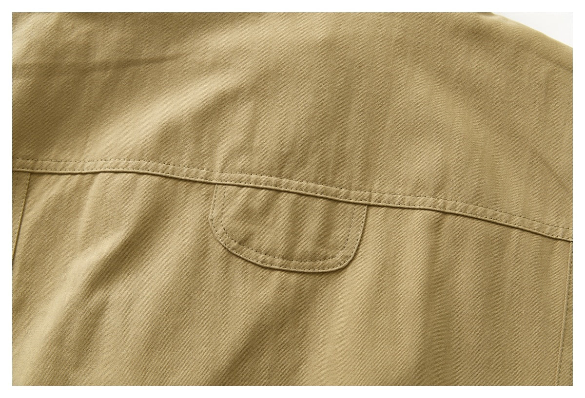Close-up of the tan jacket's back panel seam and small stitched tab.