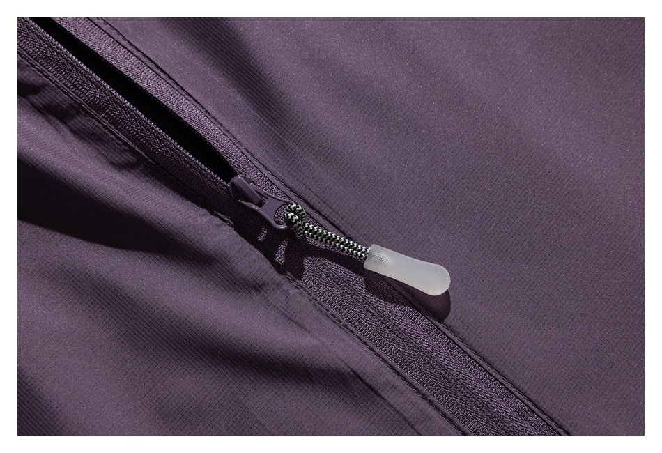 Close-up of a dark plum garment with a diagonal zipper and pale pull tab.