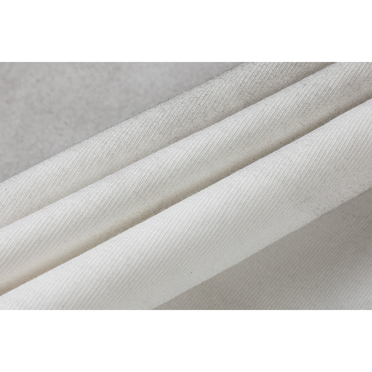 Macro view of folded off-white ribbed knit fabric.