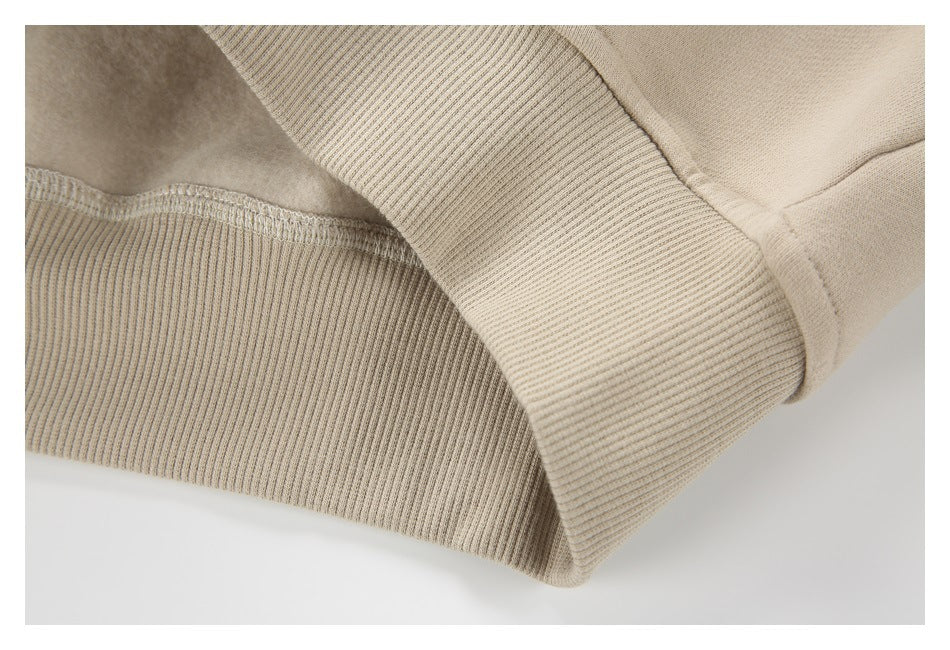 Close-up of a beige sweatshirt's ribbed cuff and hem with visible stitching.