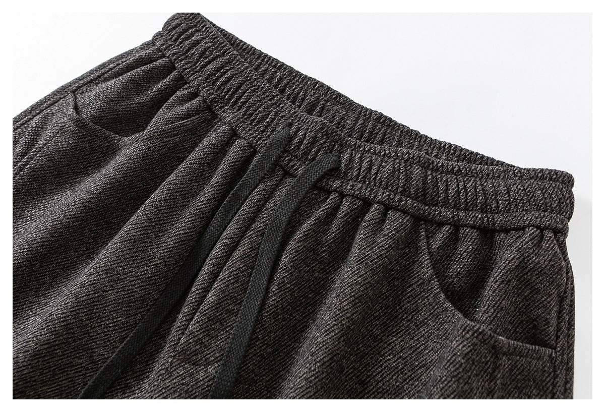 Close-up of charcoal gray marled pants showing the elastic waistband, black drawstring, and front pocket.
