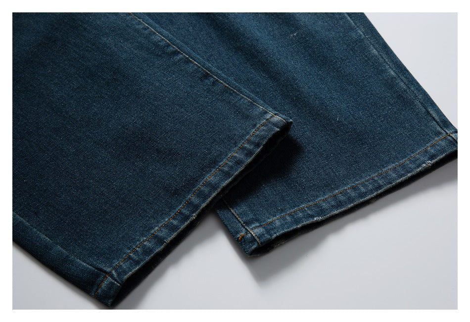 Close-up of the straight hems on dark blue jeans, showing contrast stitching and light fading.