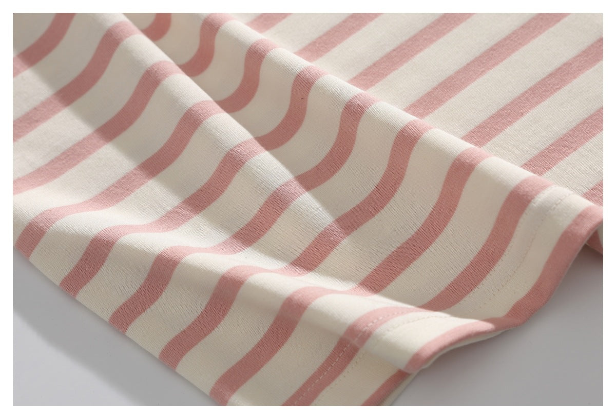 Close-up of cream fabric with dusty pink stripes, showing the drape and stitched edge.