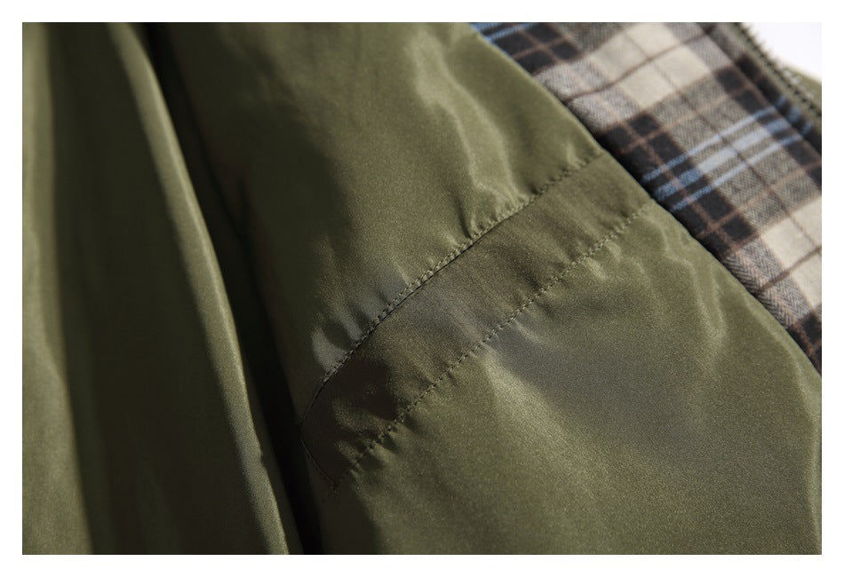 Close-up of an olive jacket's smooth inner panel and seam, with plaid lining visible at the edge.
