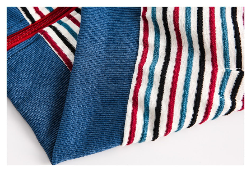 Close-up of striped garment fabric, a blue ribbed panel, and a red zipper edge.