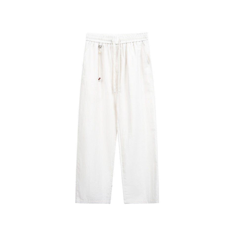 Off-white straight-leg drawstring pants with elastic waistband and beaded cord charm, front view