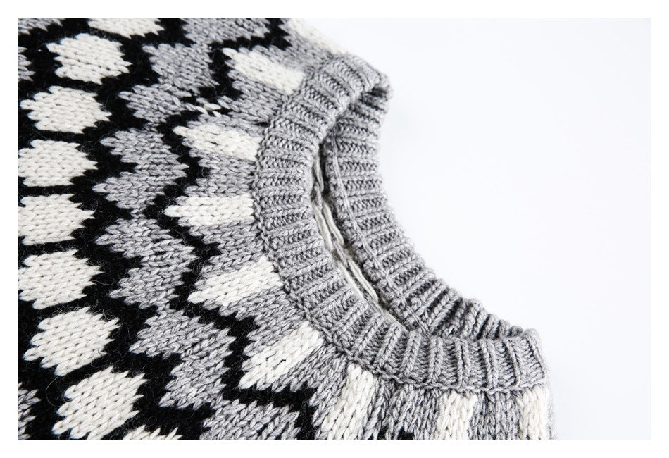 Close-up of a gray ribbed crew neckline on a black, gray, and cream patterned knit sweater.