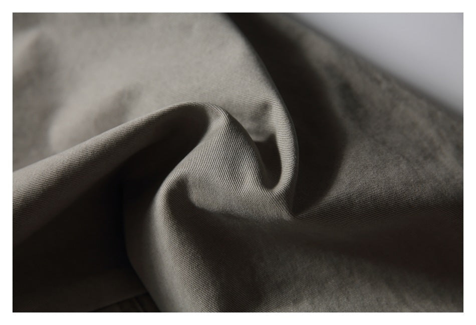 Close-up of taupe-gray garment fabric gathered into a soft fold, showing its surface and texture.
