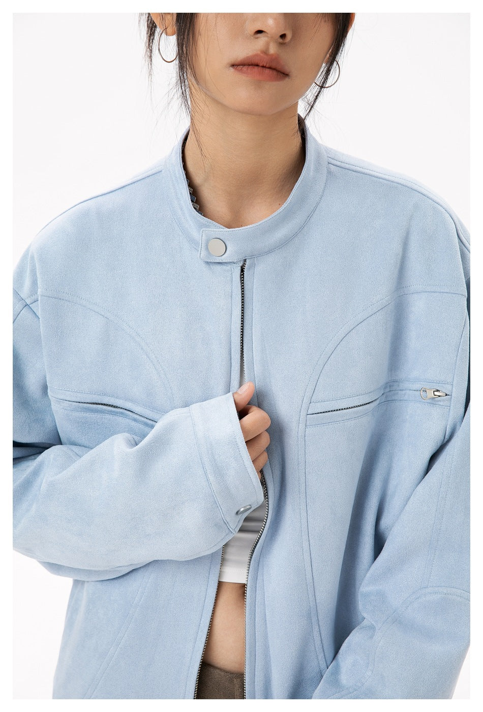 Close-up of the light blue jacket's stand collar, snap tab, front zipper, and zippered chest pockets.