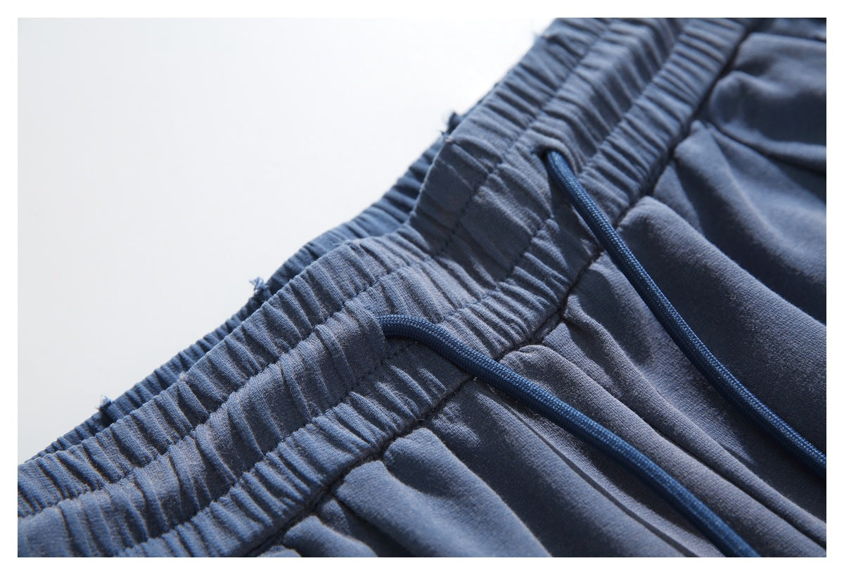 Close-up of navy pants with a gathered elastic waistband and matching drawstring.
