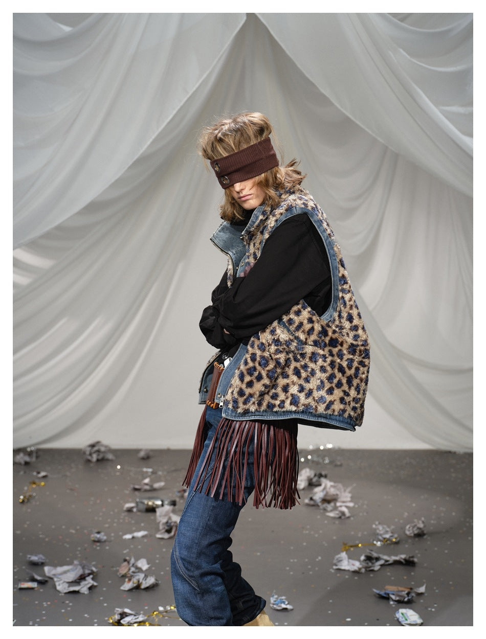 Side view shows the leopard-print vest's denim-trimmed armhole and long burgundy fringe over jeans.