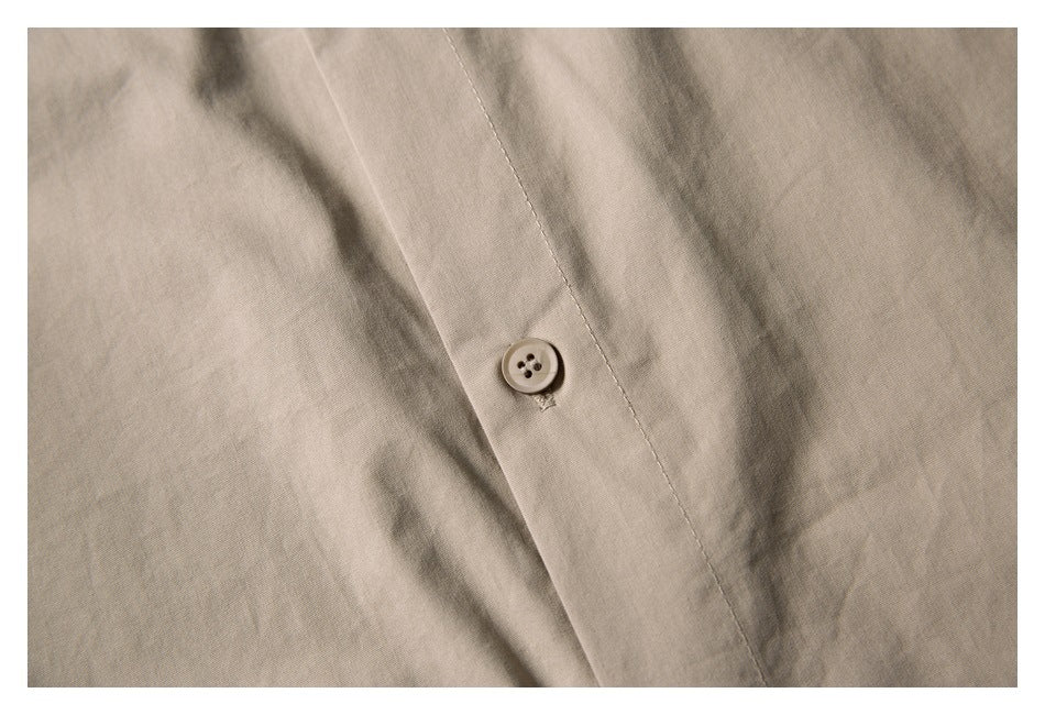 Close-up of a light beige four-hole button and stitching on a garment.