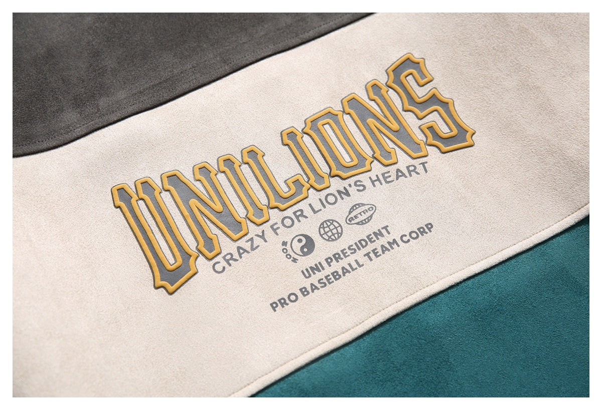 Close-up of mustard outlined lettering and smaller gray text printed on a cream garment panel.